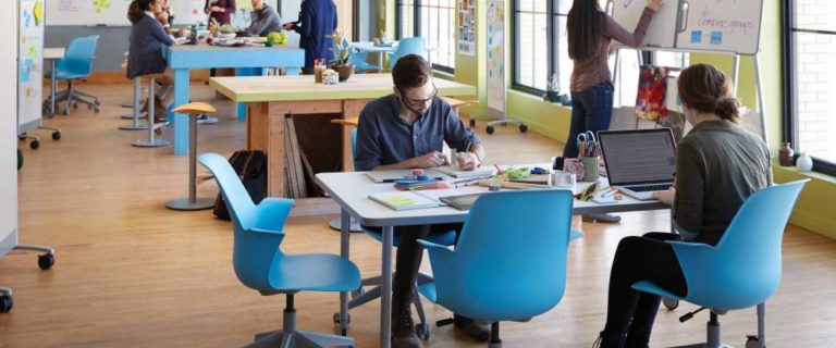 Studenten aan het werk aan tafels in een creatieve werkruimte