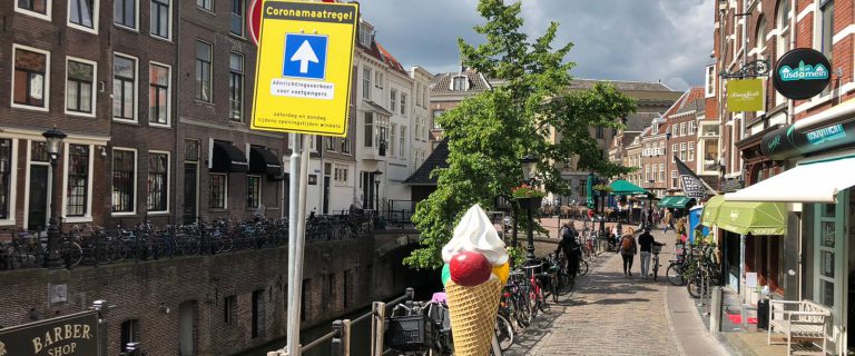 Foto toont een Utrechtse gracht met een verkeersbord dat het icoon voor een eenrichtingsverkeersweg toont en de tekst 'Coronamaatregel'.