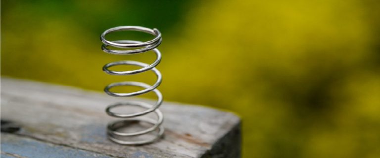 We zien een springveer op een tafelblad, tegen een vervaagde achtergrond