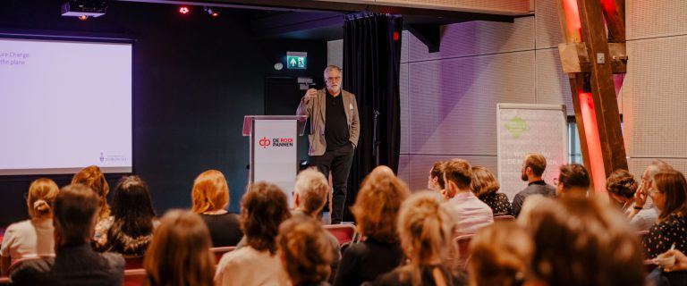 John Robinson spreekt de zaal toe tijdens de Leermiddag.